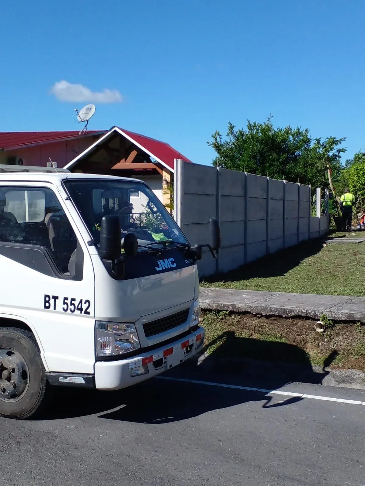 Camión de transporte junto a muro perimetral prefabricado recién instalado en zona residencial