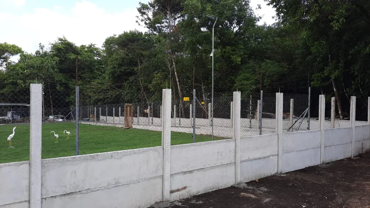 Muro perimetral prefabricado bajo con cerca de alambre superior en finca con gallinas