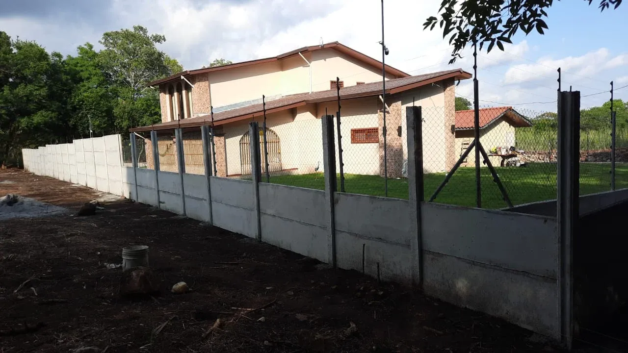 Residencia tipo finca con muro perimetral prefabricado alto y cerca de alambre como refuerzo