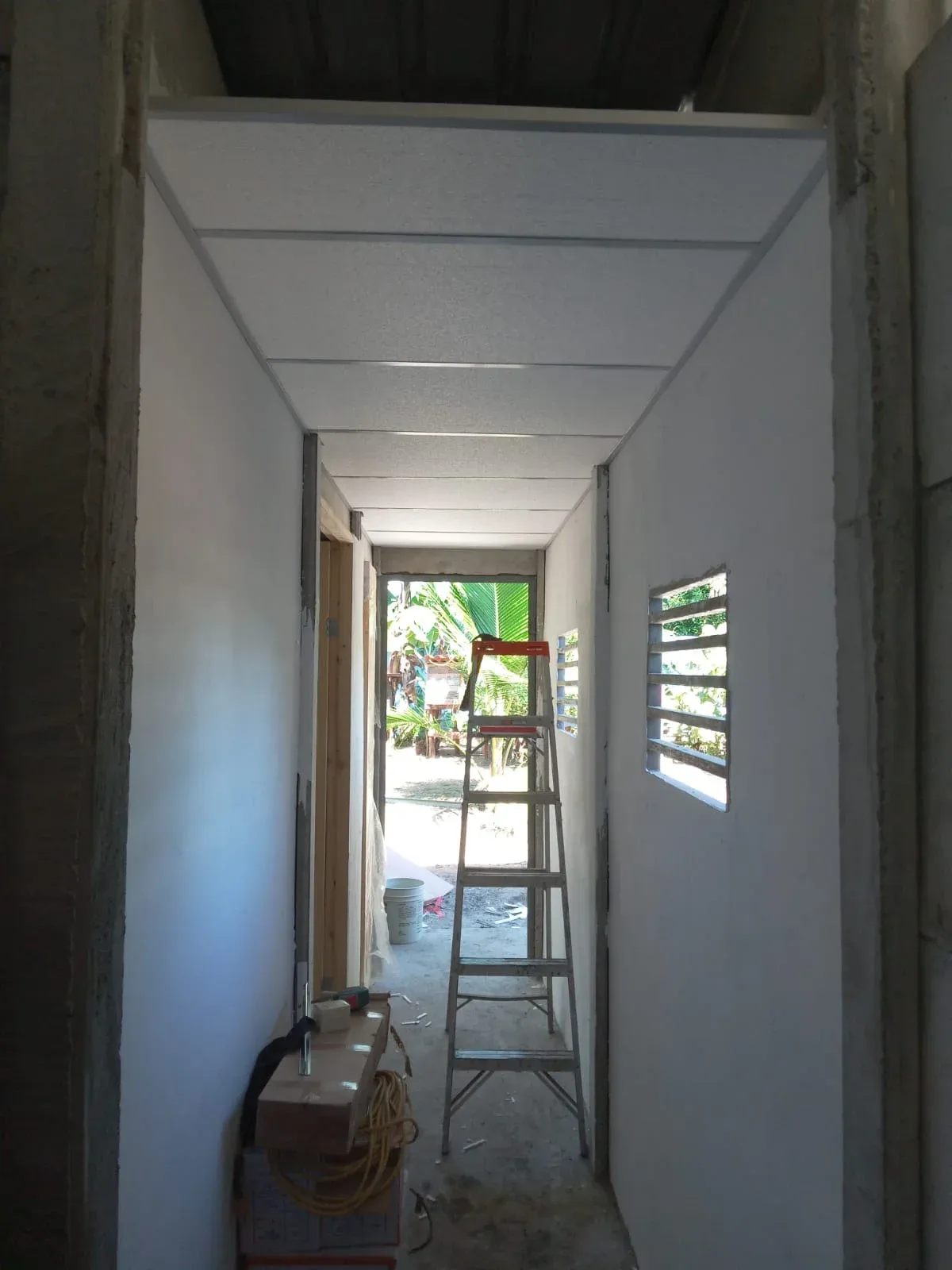 Vista interior de anexo con cielo raso de PVC blanco y escalera en proceso de terminación
