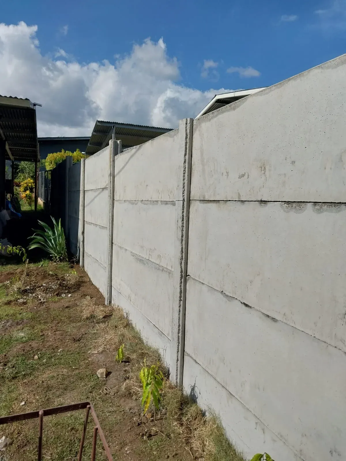Muro perimetral prefabricado terminado entre dos residencias con jardín delantero