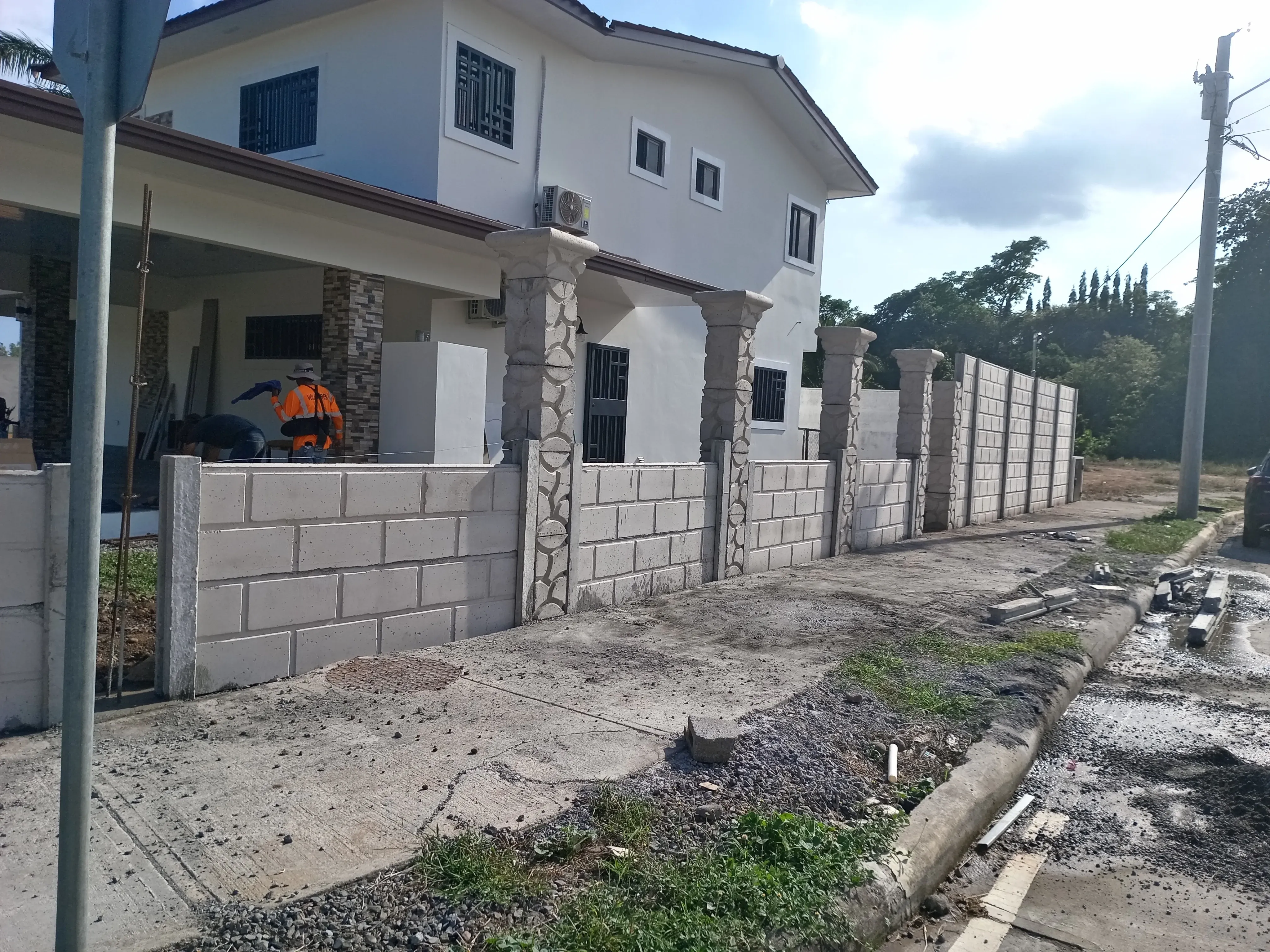 Residencia con muro perimetral bajo y columnas decorativas revestidas en piedra natural