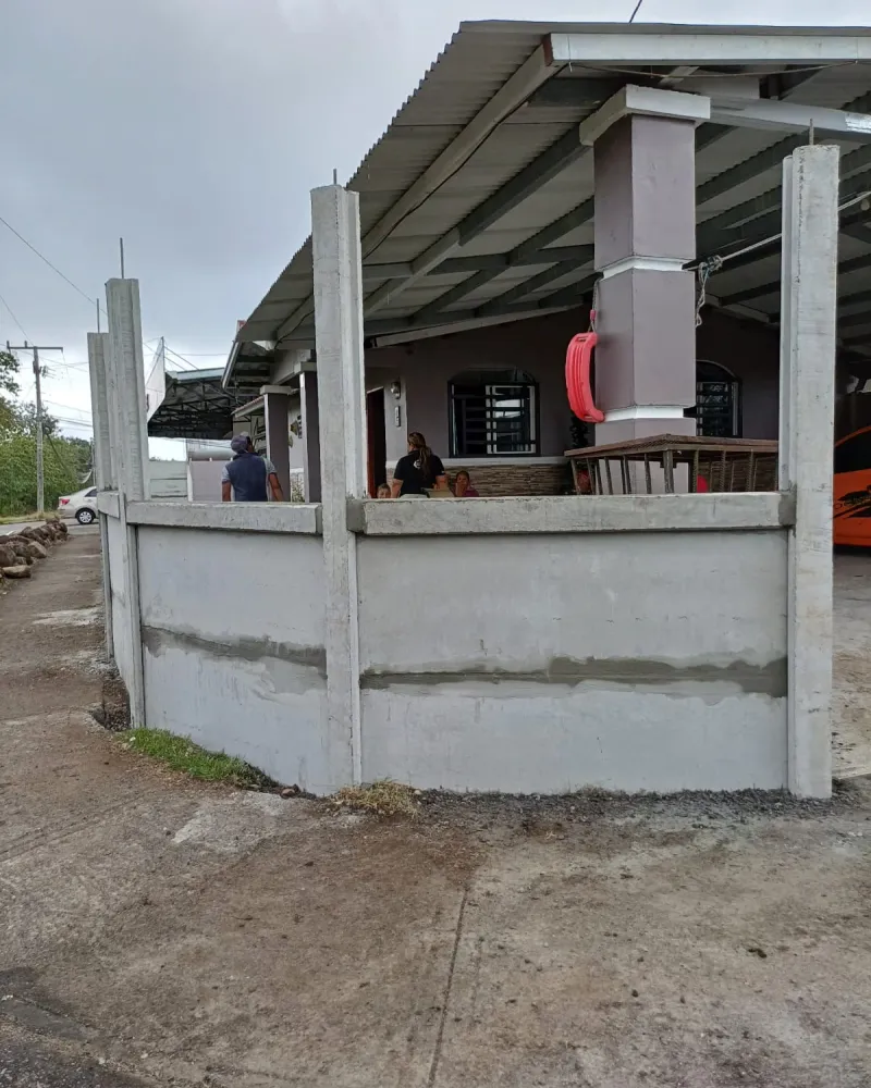 Muro perimetral URBEXA alto en frente urbano de residencia con techo de teja